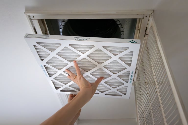 Adult homeowner installing a new air filter in an intake vent in a home ceiling