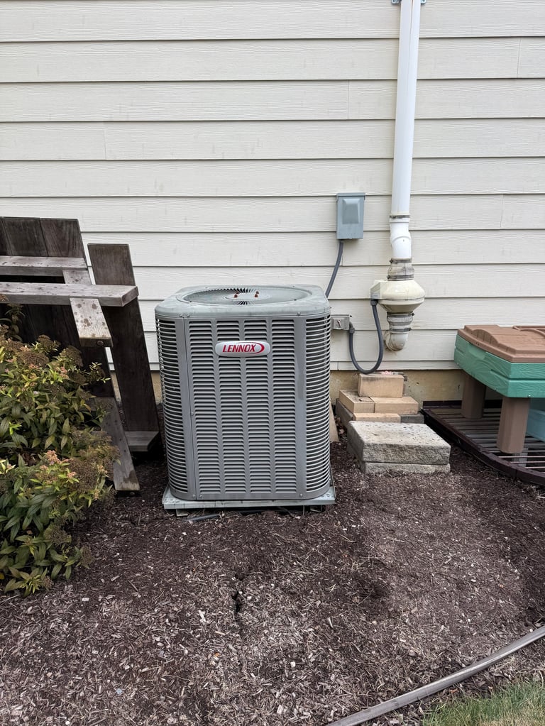 Lennox air conditioning unit installed against a beige siding house wall with white PVC pipes and electrical connections