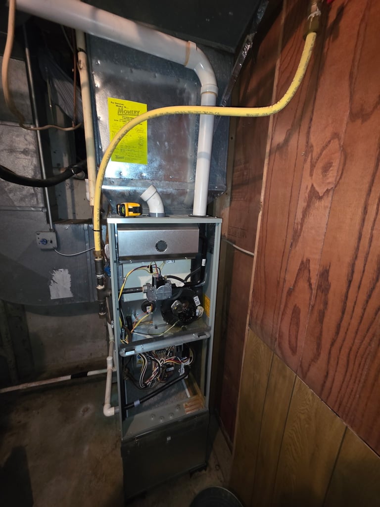 Open HVAC furnace unit with yellow gas line attached, mounted in basement corner against wooden wall