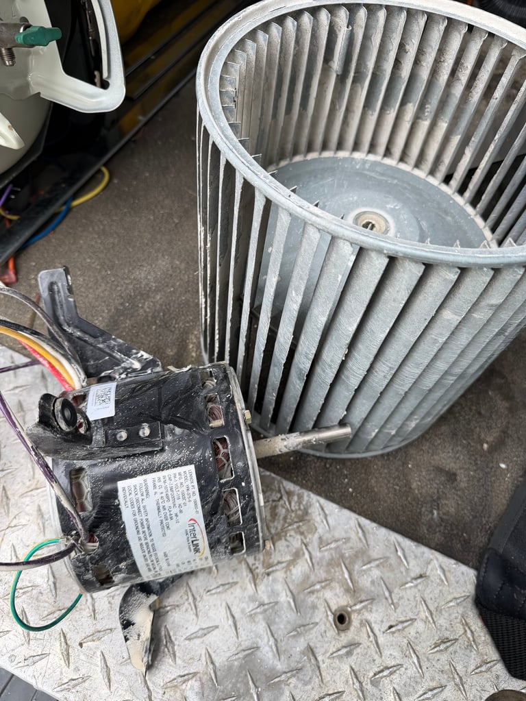 HVAC blower motor assembly with barrel-shaped fan housing and electrical motor component on garage floor