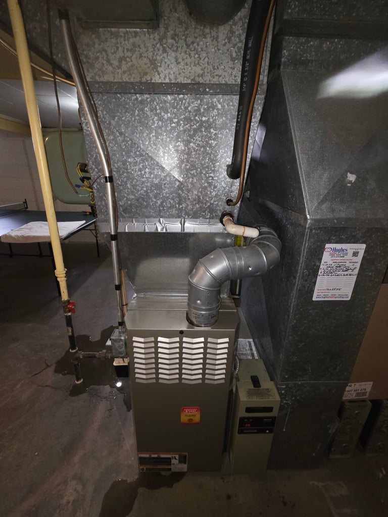 HVAC furnace unit in basement with metal ductwork and piping connected to gray walls