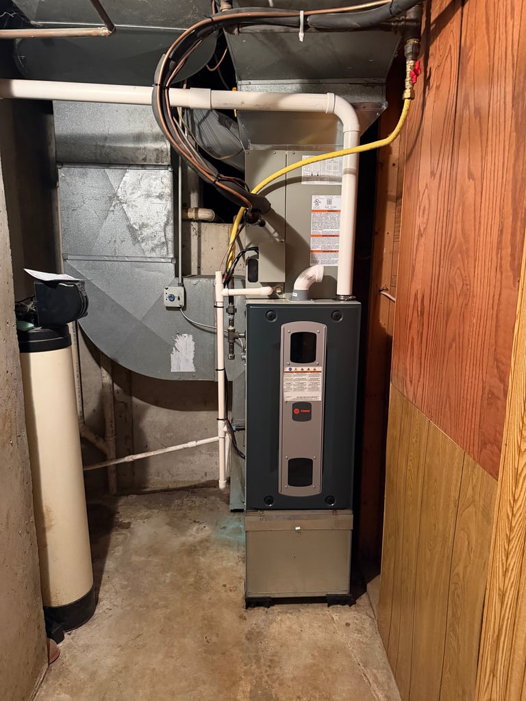 HVAC furnace and water heater system installed in a basement utility room with metal ductwork and pipes