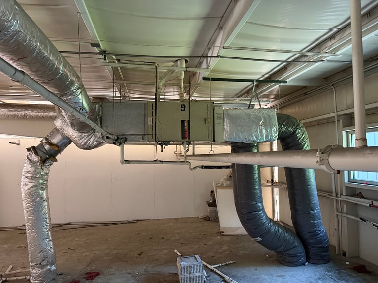 Industrial ceiling with metal ductwork and HVAC piping system installation in an empty warehouse space