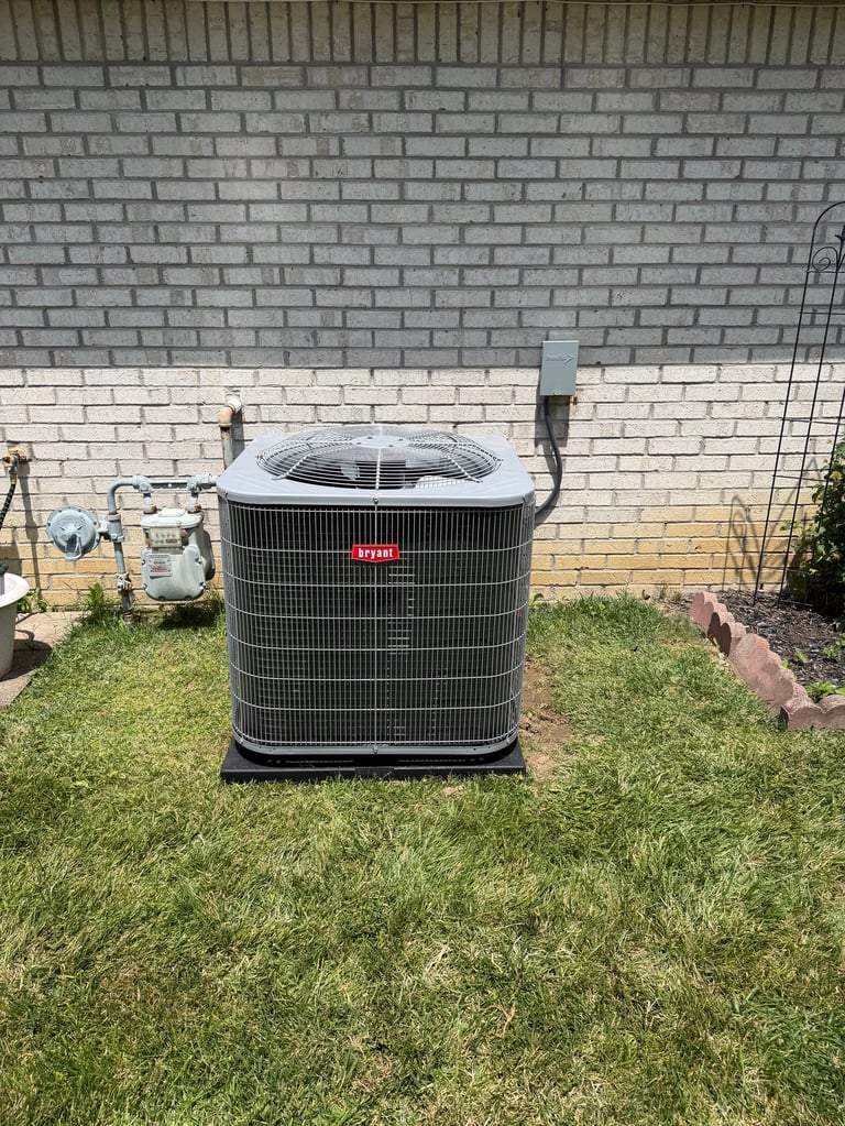 Outdoor HVAC air conditioning unit installed on grass against a brick foundation wall