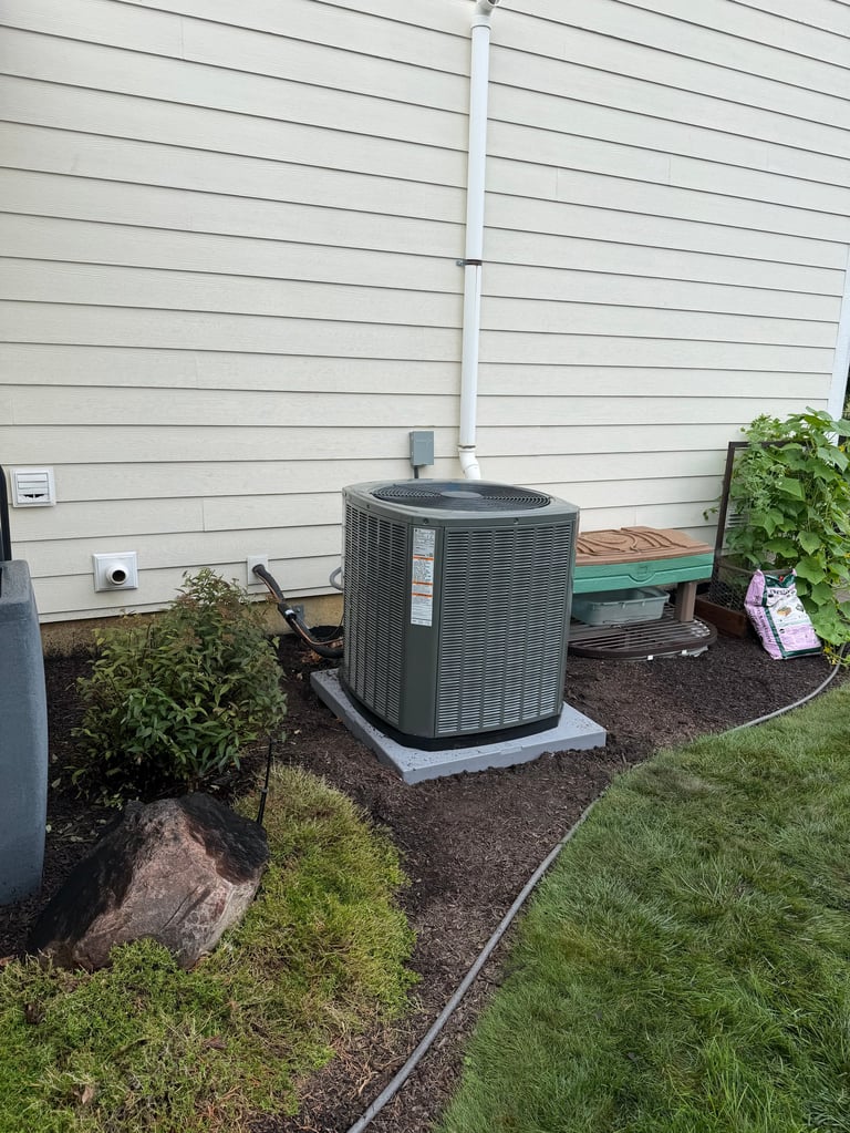 Outdoor HVAC air conditioning unit installed on gravel pad against white vinyl siding with white downspout