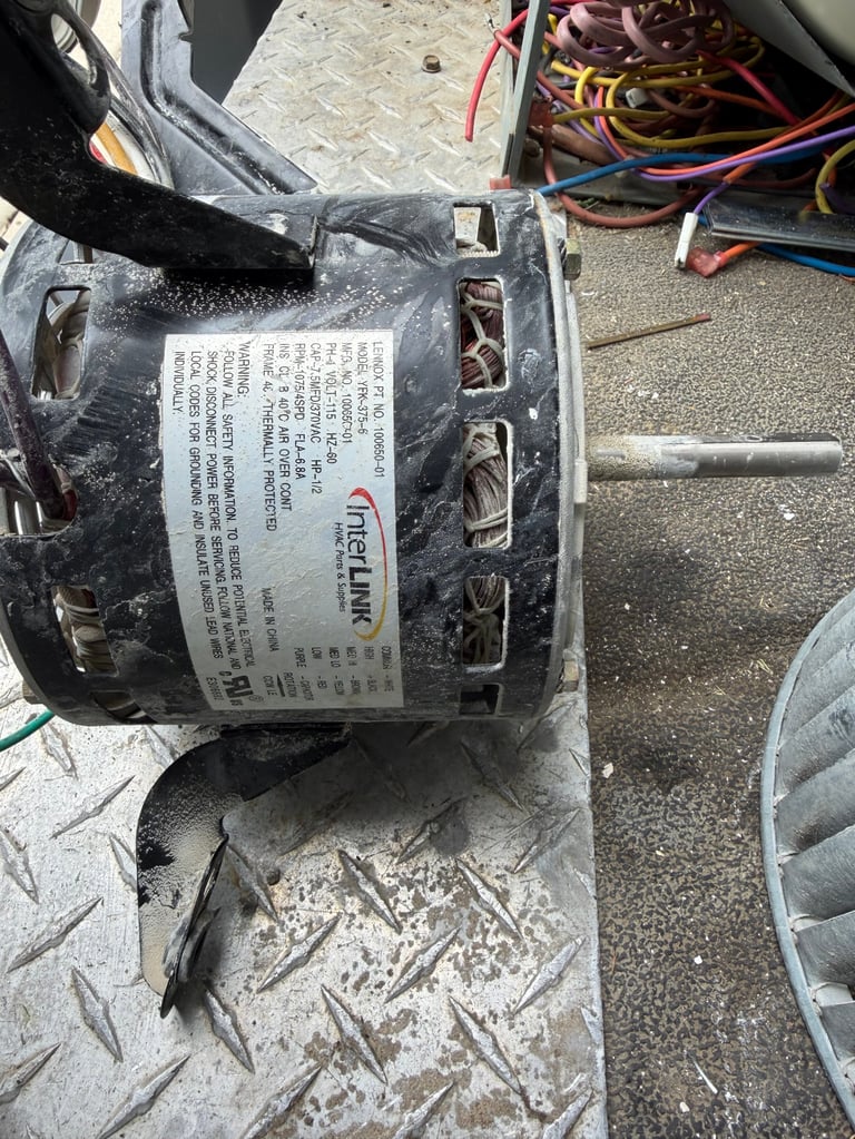 Disassembled electric motor with label and wiring visible on metal work surface
