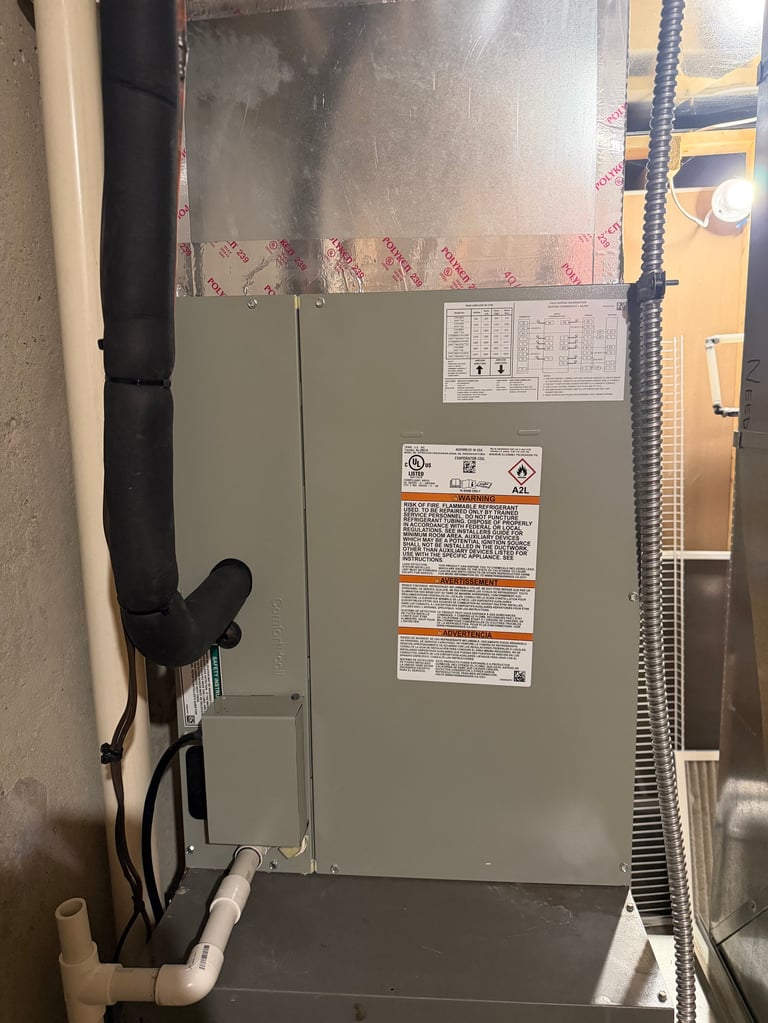 Beige HVAC furnace unit mounted on wall with warning labels, pipes, and electrical connections in basement