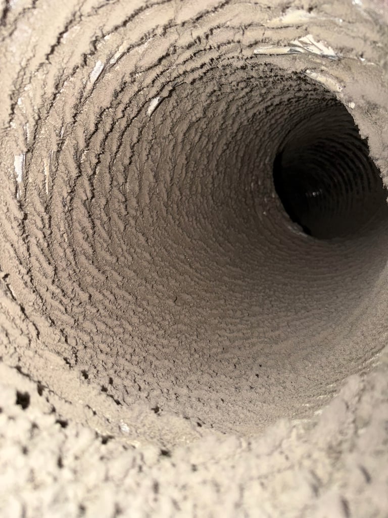 Interior view of a circular duct or pipe with textured concrete walls spiraling inward to darkness