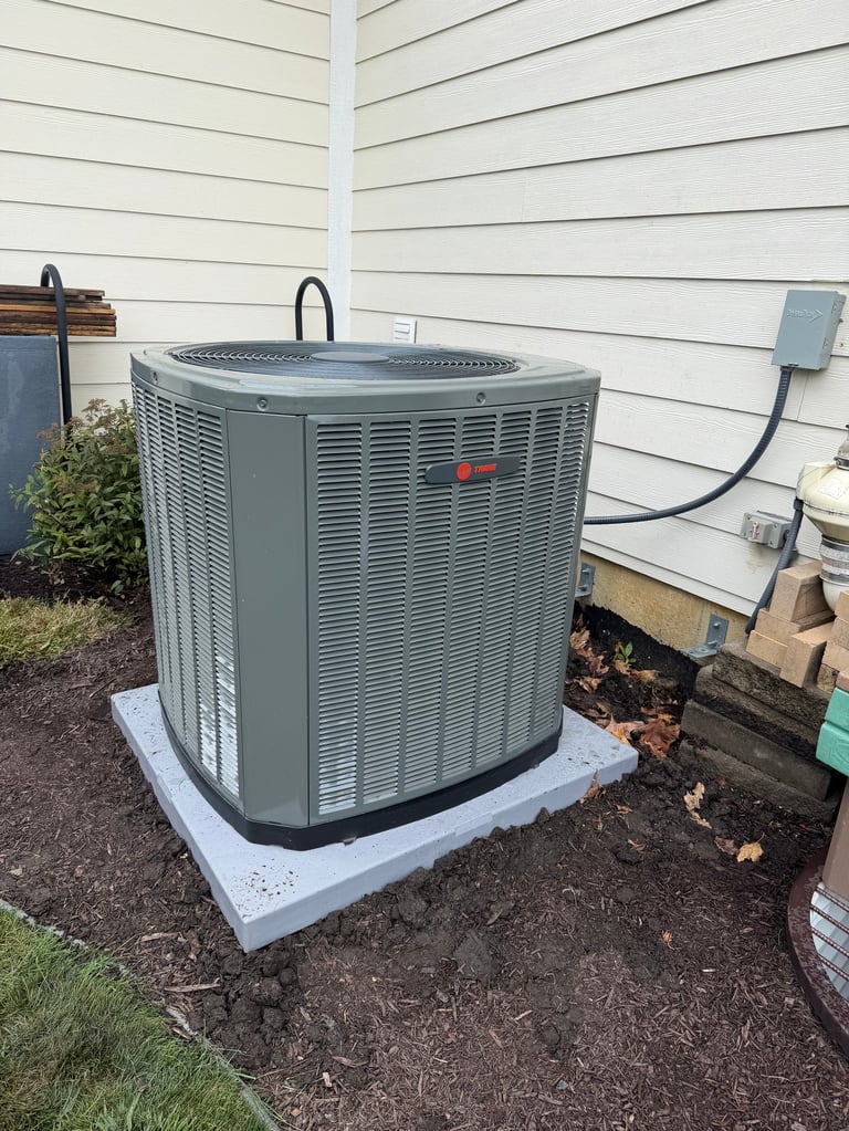 Gray HVAC air conditioning unit mounted on concrete pad against house with white siding