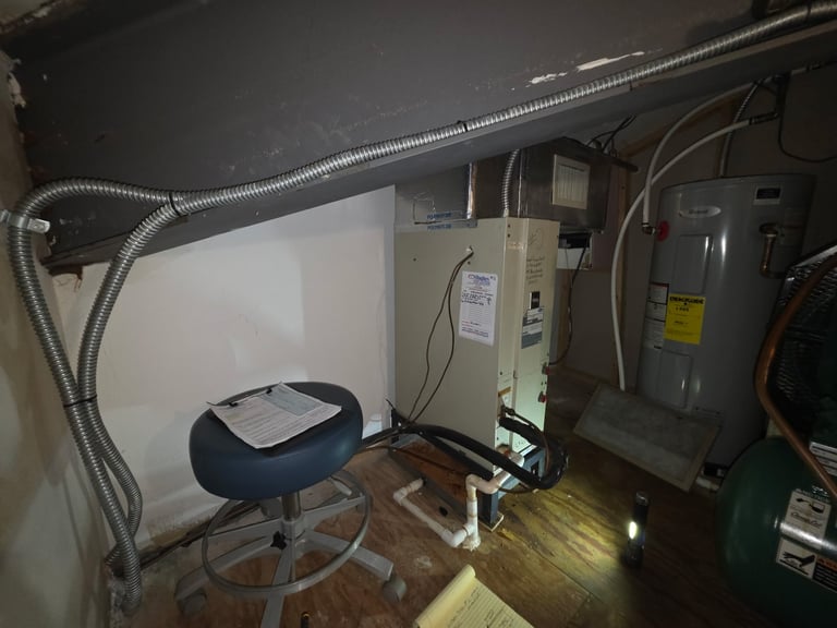Interior view of an electrical service panel room with metal conduit, control boxes, a blue stool, and circuit breaker panel on wall