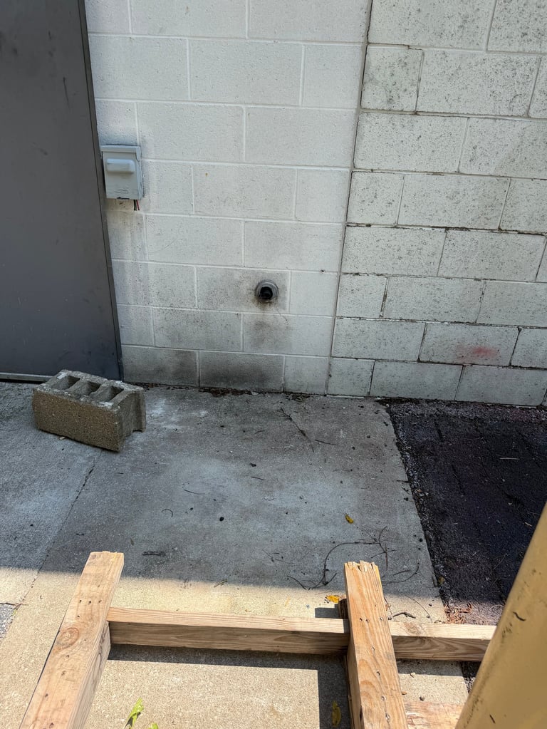 Concrete floor with wooden framing and concrete block wall during construction, showing foundation work in progress.